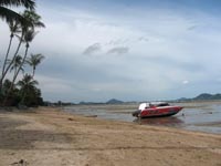 A speedboat rests on the exposed seabed of Friendship Beach